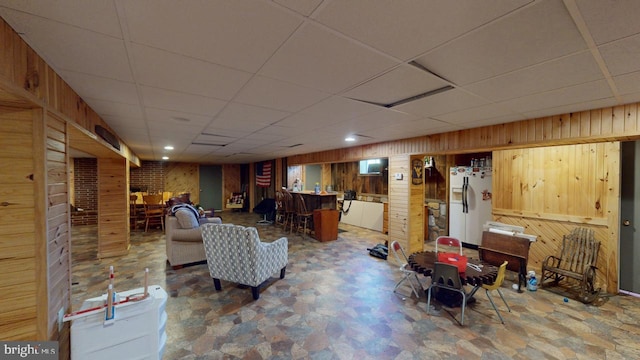 interior space with wooden walls, a drop ceiling, and bar