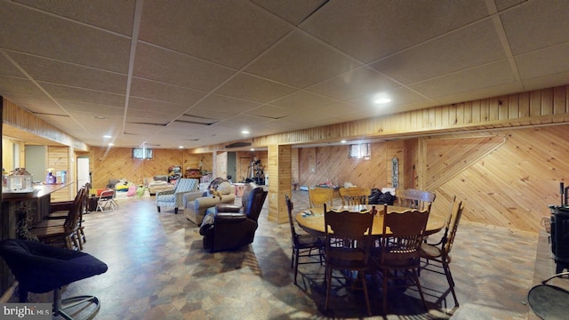 dining area featuring a paneled ceiling and wooden walls