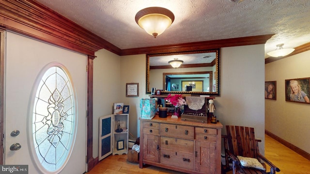 foyer featuring light wood-type flooring, a textured ceiling, baseboards, and ornamental molding