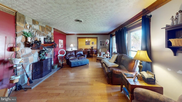 living room featuring crown molding, a fireplace, wood-type flooring, and a textured ceiling