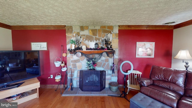 living room featuring crown molding, a textured ceiling, hardwood / wood-style flooring, and a fireplace