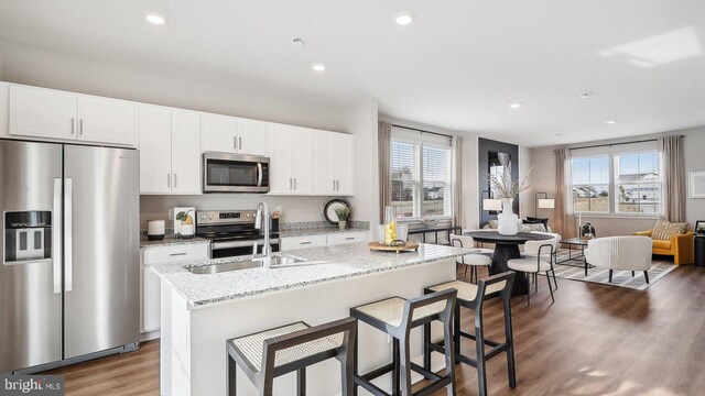 kitchen with a center island with sink, sink, a healthy amount of sunlight, and appliances with stainless steel finishes