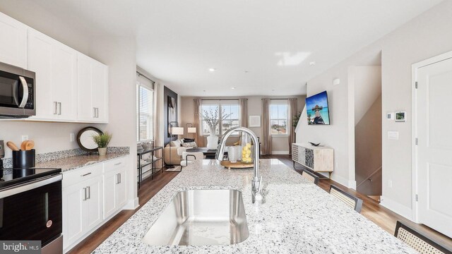 kitchen featuring stainless steel appliances, sink, light stone countertops, dark hardwood / wood-style floors, and white cabinets