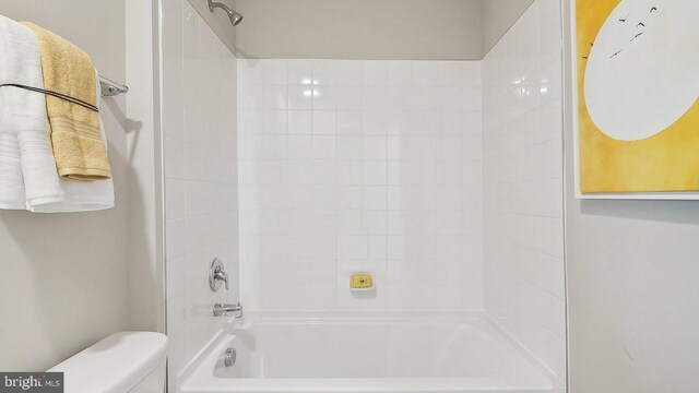 bathroom with toilet and tiled shower / bath combo