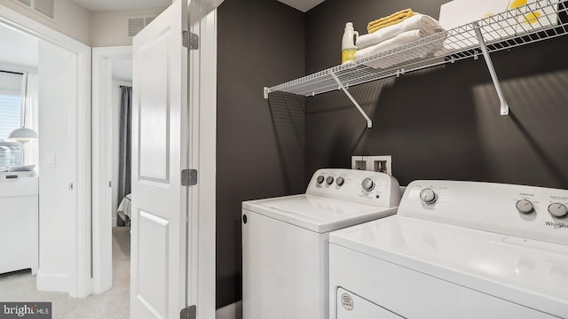 washroom with washing machine and clothes dryer and light carpet