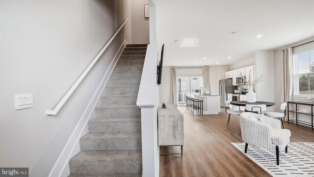 staircase featuring sink and hardwood / wood-style flooring