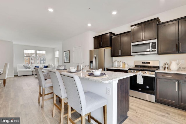 kitchen featuring a kitchen island with sink, stainless steel appliances, and light hardwood / wood-style floors