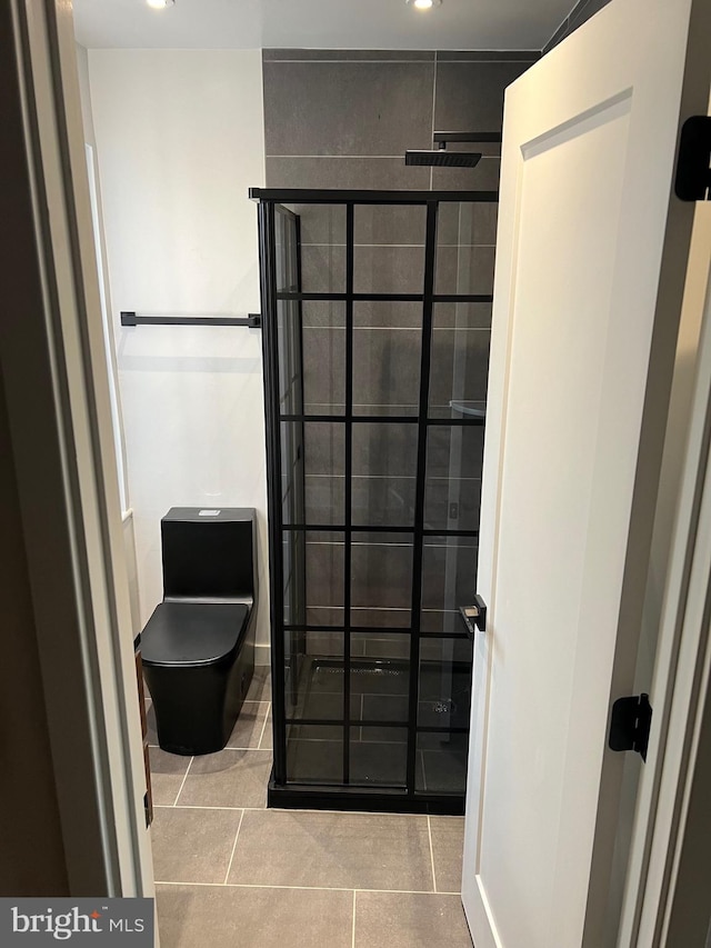 bathroom featuring tile patterned floors, tiled shower, and toilet