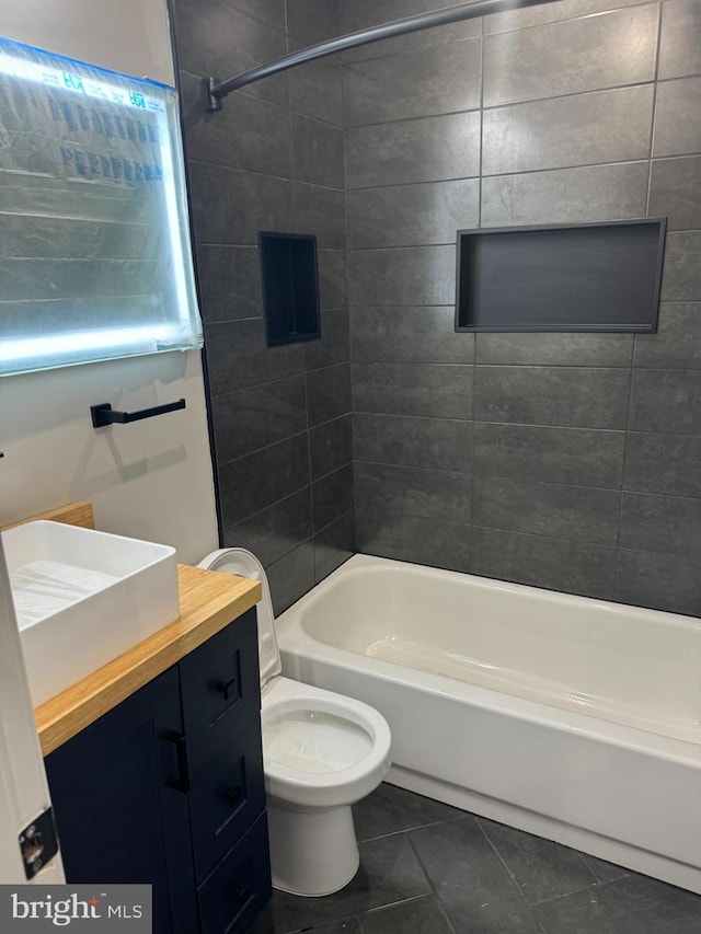 full bathroom with tile patterned floors, vanity, tiled shower / bath combo, and toilet