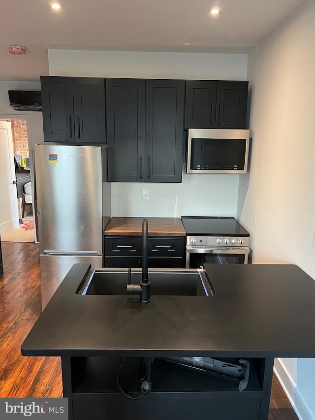 kitchen featuring sink, a kitchen breakfast bar, dark hardwood / wood-style floors, a kitchen island with sink, and appliances with stainless steel finishes