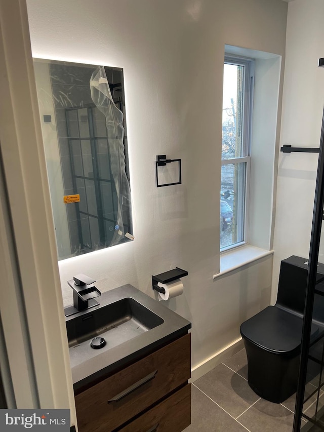 bathroom with toilet, vanity, and tile patterned floors