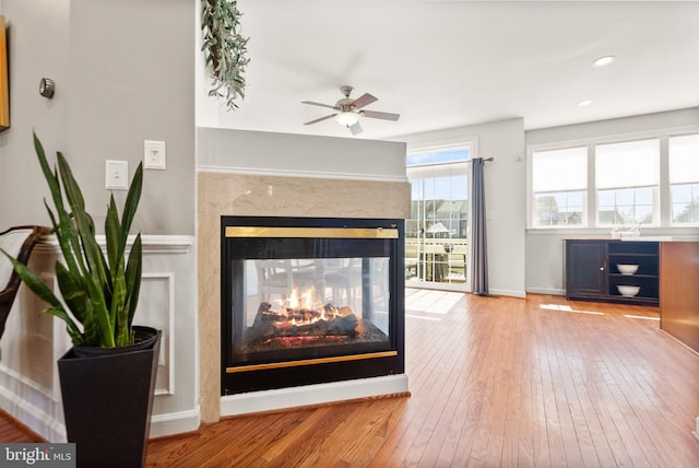 details featuring wood finished floors, baseboards, recessed lighting, a multi sided fireplace, and ceiling fan