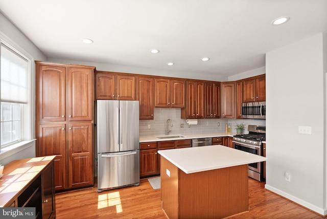 kitchen with a sink, appliances with stainless steel finishes, light wood-style flooring, and a healthy amount of sunlight