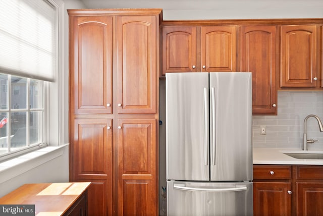 kitchen featuring a sink, a healthy amount of sunlight, light countertops, and freestanding refrigerator