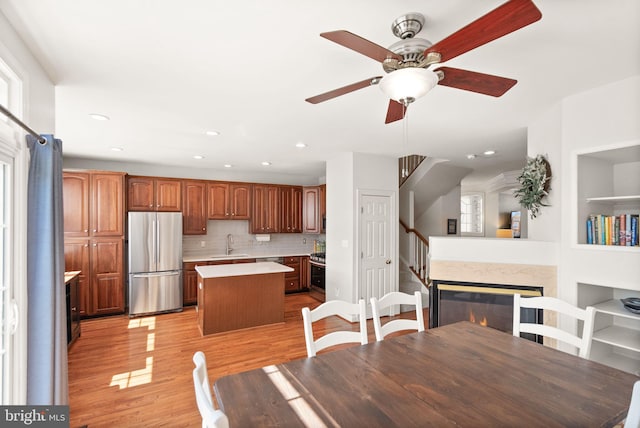 dining space with a glass covered fireplace, recessed lighting, a ceiling fan, and light wood-type flooring