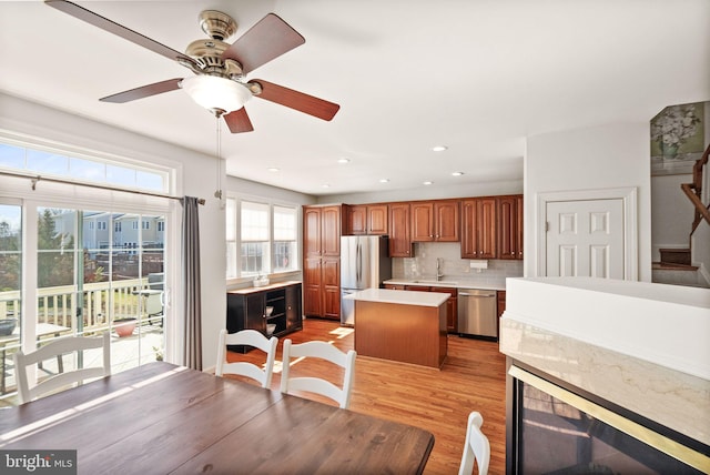 kitchen featuring a sink, a kitchen island, appliances with stainless steel finishes, light countertops, and decorative backsplash