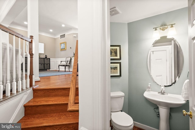 half bathroom featuring visible vents, toilet, wood finished floors, and ornamental molding