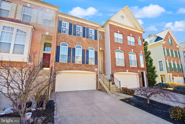 townhome / multi-family property with an attached garage, brick siding, and driveway