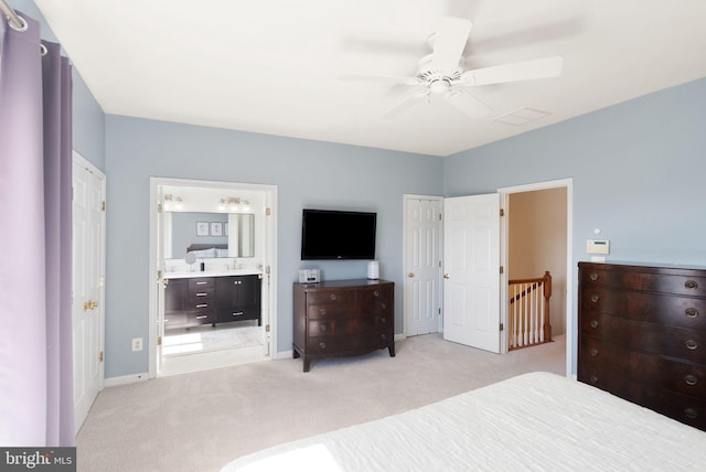 bedroom with ensuite bath, light colored carpet, baseboards, and ceiling fan