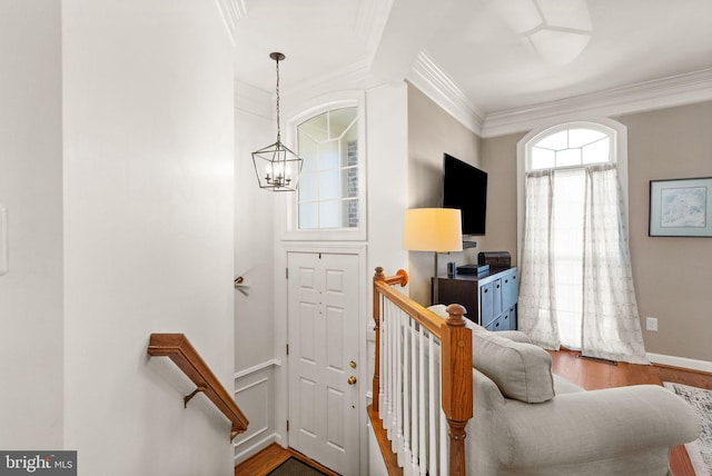 stairs with crown molding, wood finished floors, baseboards, and a chandelier