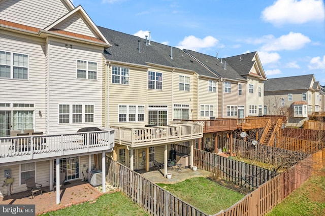 rear view of property featuring a lawn, a patio, a fenced backyard, a residential view, and a shingled roof