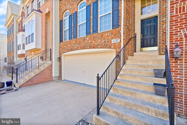 property entrance featuring concrete driveway, brick siding, and a garage