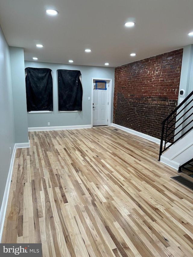 interior space with light hardwood / wood-style floors and brick wall