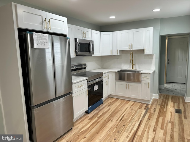 kitchen featuring sink, white cabinetry, stainless steel appliances, and light wood-type flooring