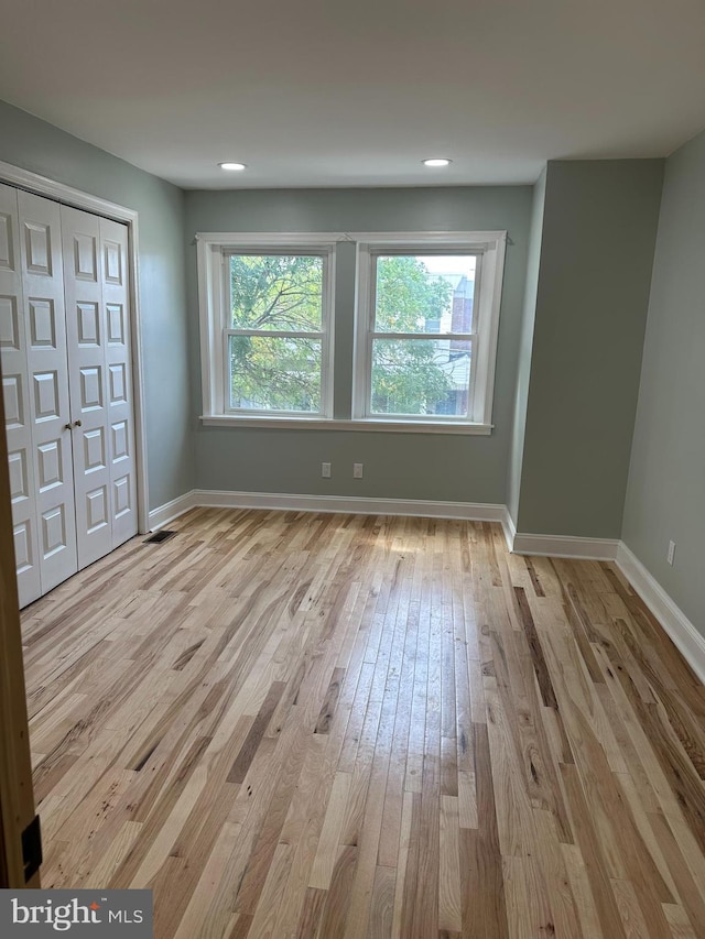 spare room featuring light wood-type flooring and a healthy amount of sunlight