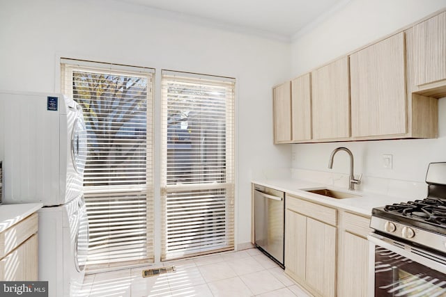 kitchen with light brown cabinets, stainless steel appliances, sink, and stacked washer / drying machine