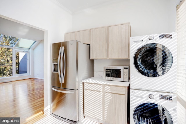 kitchen featuring stacked washing maching and dryer, crown molding, appliances with stainless steel finishes, light brown cabinets, and light hardwood / wood-style flooring