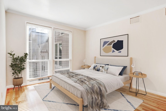 bedroom featuring ornamental molding and light hardwood / wood-style floors