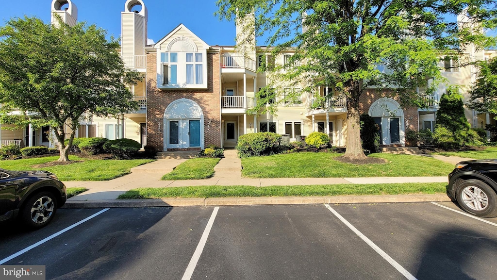 view of front of house featuring a balcony and a front lawn