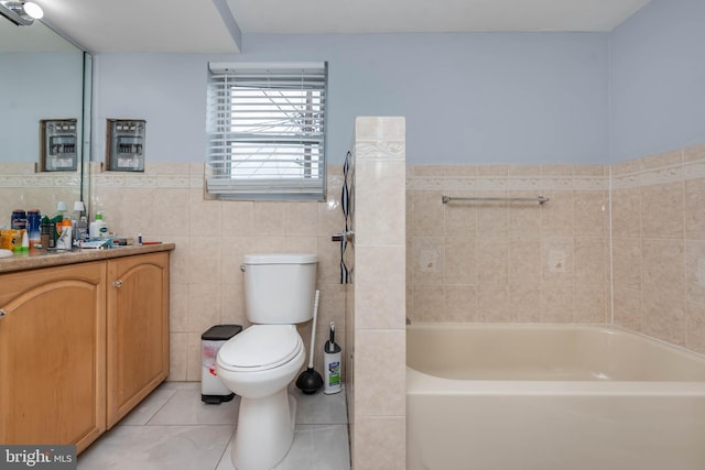 bathroom with tile walls, a tub to relax in, vanity, tile patterned flooring, and toilet