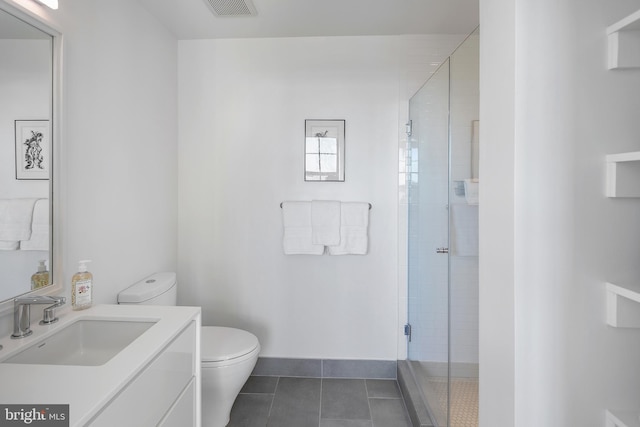 bathroom featuring toilet, vanity, tile patterned floors, and a shower with shower door