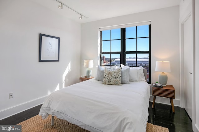 bedroom with track lighting and dark hardwood / wood-style floors