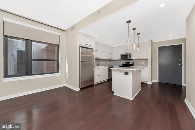 kitchen with a center island, dark hardwood / wood-style floors, white cabinets, hanging light fixtures, and stainless steel appliances