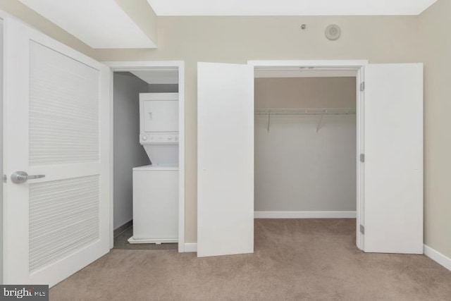 interior space with light carpet, a closet, and stacked washer and dryer