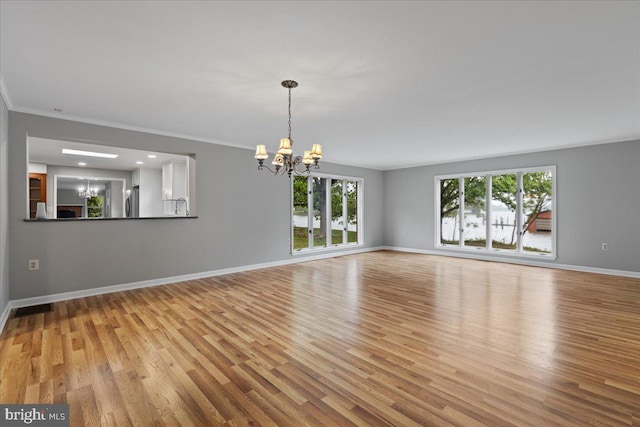 spare room featuring light hardwood / wood-style floors, ornamental molding, and a chandelier