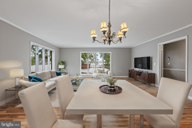 dining area with light hardwood / wood-style flooring, a wealth of natural light, a notable chandelier, and ornamental molding