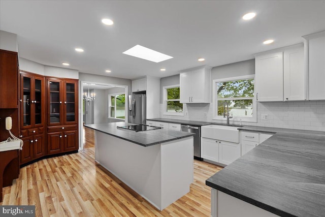 kitchen with light hardwood / wood-style flooring, stainless steel appliances, white cabinetry, and a kitchen island