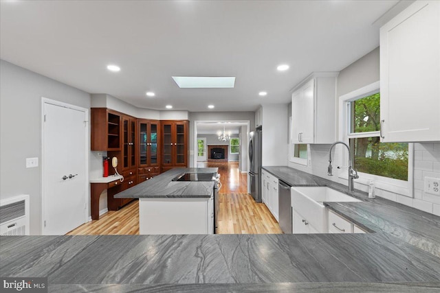 kitchen with light hardwood / wood-style floors, sink, white cabinetry, decorative backsplash, and appliances with stainless steel finishes