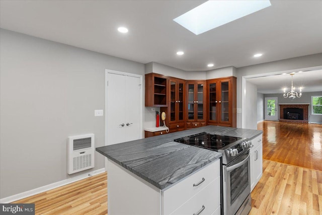 kitchen with white cabinets, stainless steel electric range, light hardwood / wood-style floors, and heating unit