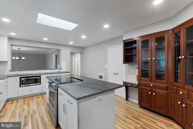 kitchen with decorative light fixtures, stainless steel appliances, and white cabinets