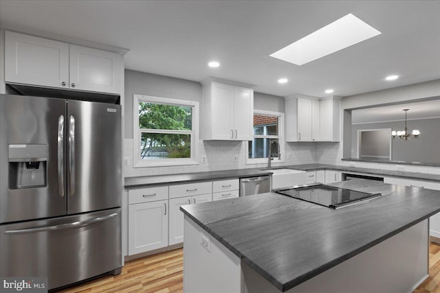 kitchen with light wood-type flooring, white cabinets, appliances with stainless steel finishes, and a center island