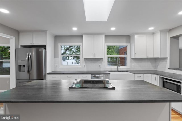 kitchen with sink, stainless steel appliances, white cabinetry, and a kitchen island