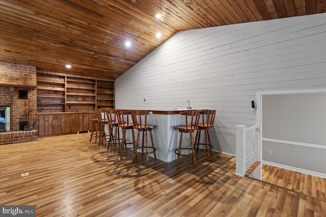 interior space with wooden ceiling, lofted ceiling, built in shelves, and hardwood / wood-style flooring