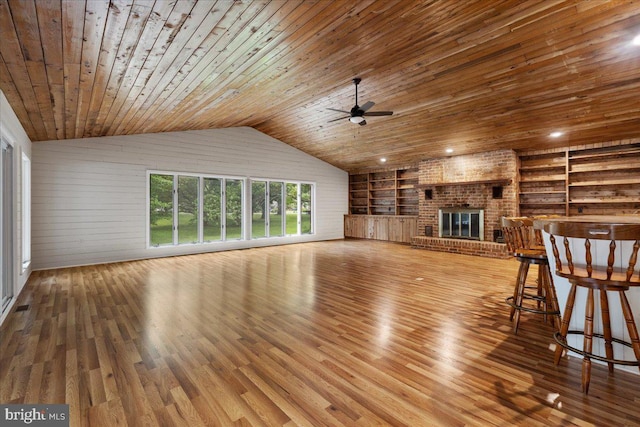 unfurnished living room featuring built in shelves, wood ceiling, hardwood / wood-style floors, a brick fireplace, and vaulted ceiling