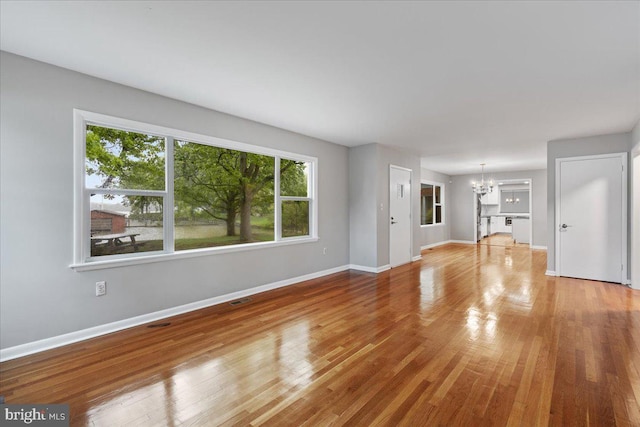 unfurnished living room featuring a notable chandelier and wood-type flooring