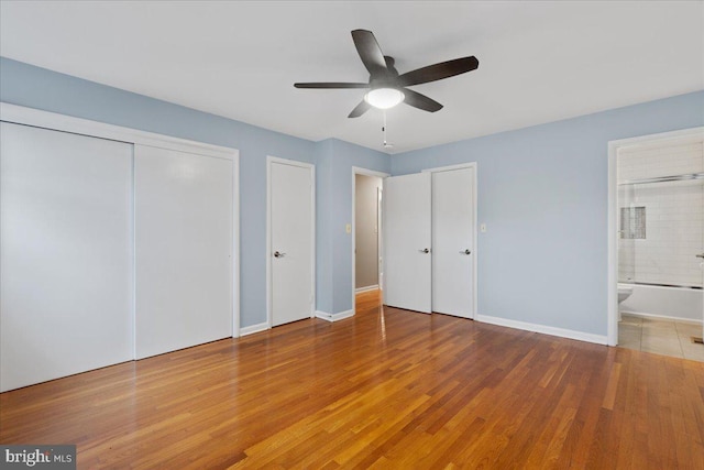 unfurnished bedroom with wood-type flooring, ceiling fan, and connected bathroom